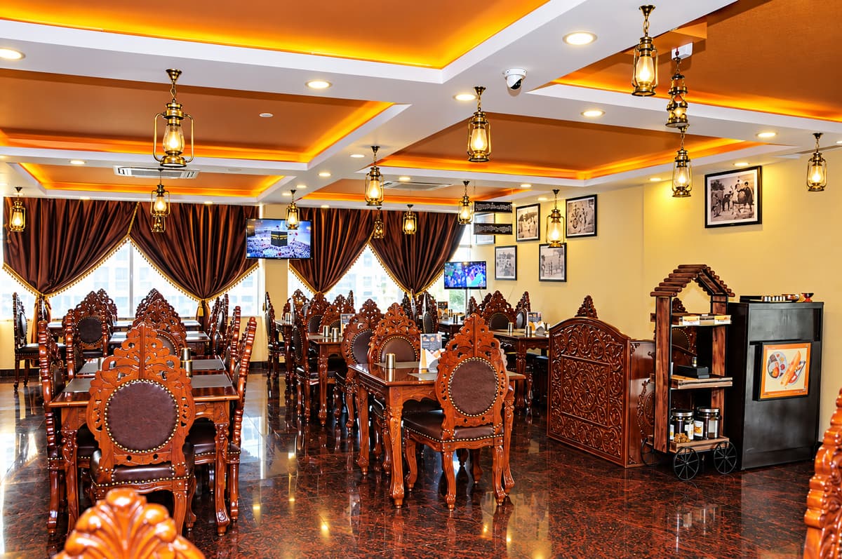 The hotel restaurant with hand-carved wooden chairs, brass lantern lights and a polished granite floor